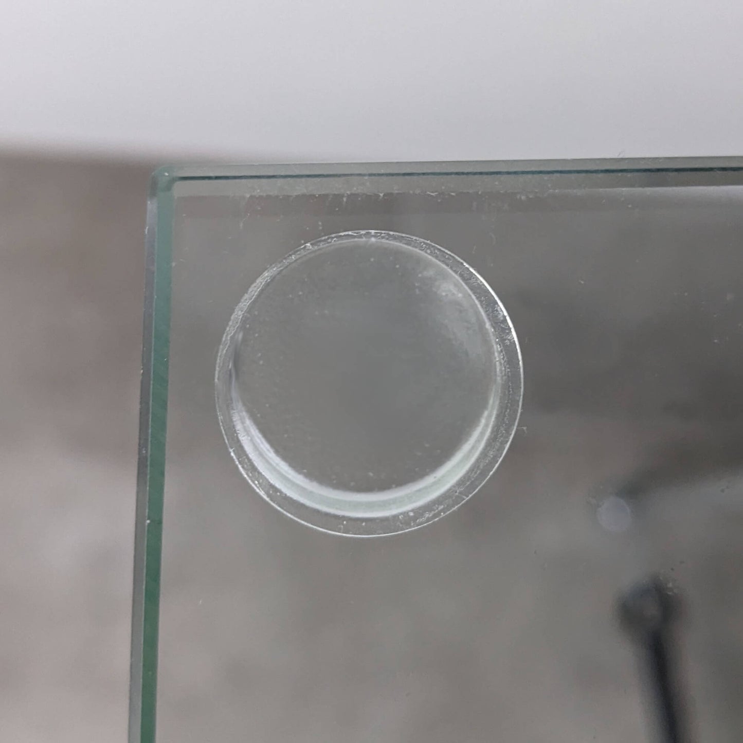 A clear flat topped bumper foot used on a glass door to stop the glass from breaking when it makes contact with a wall.