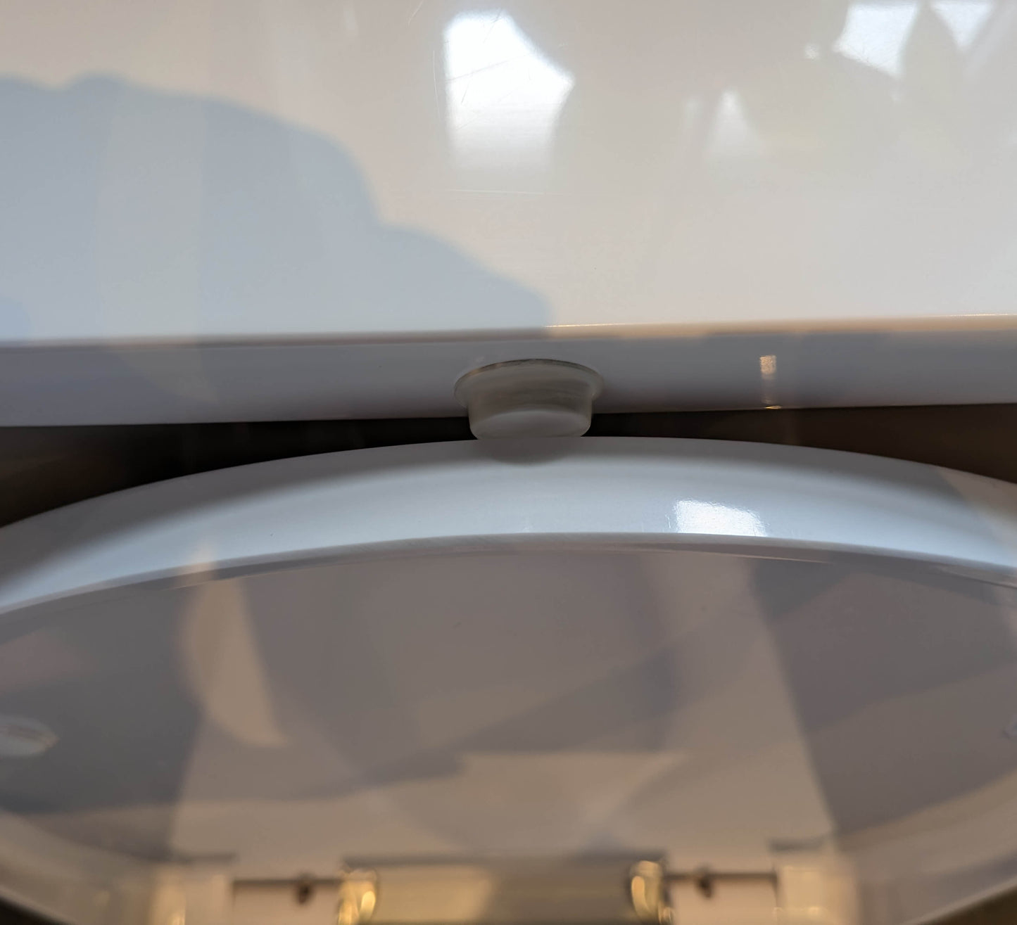 A clear flat topped bumper used in a toilet to prevent a banging noise when a toilet lid is being closed.