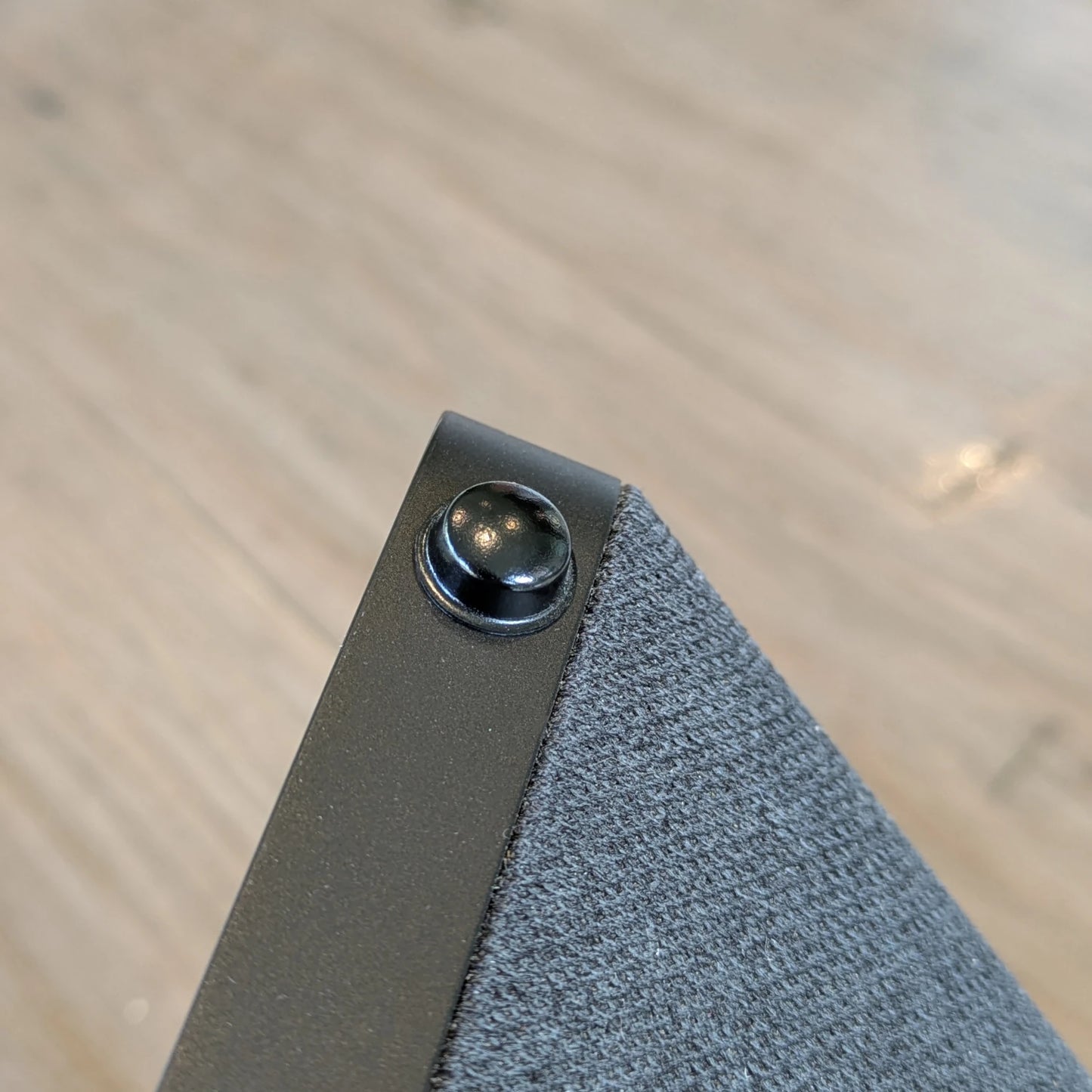 A black dome topped bumper foot being used on the base of an electronic speaker.