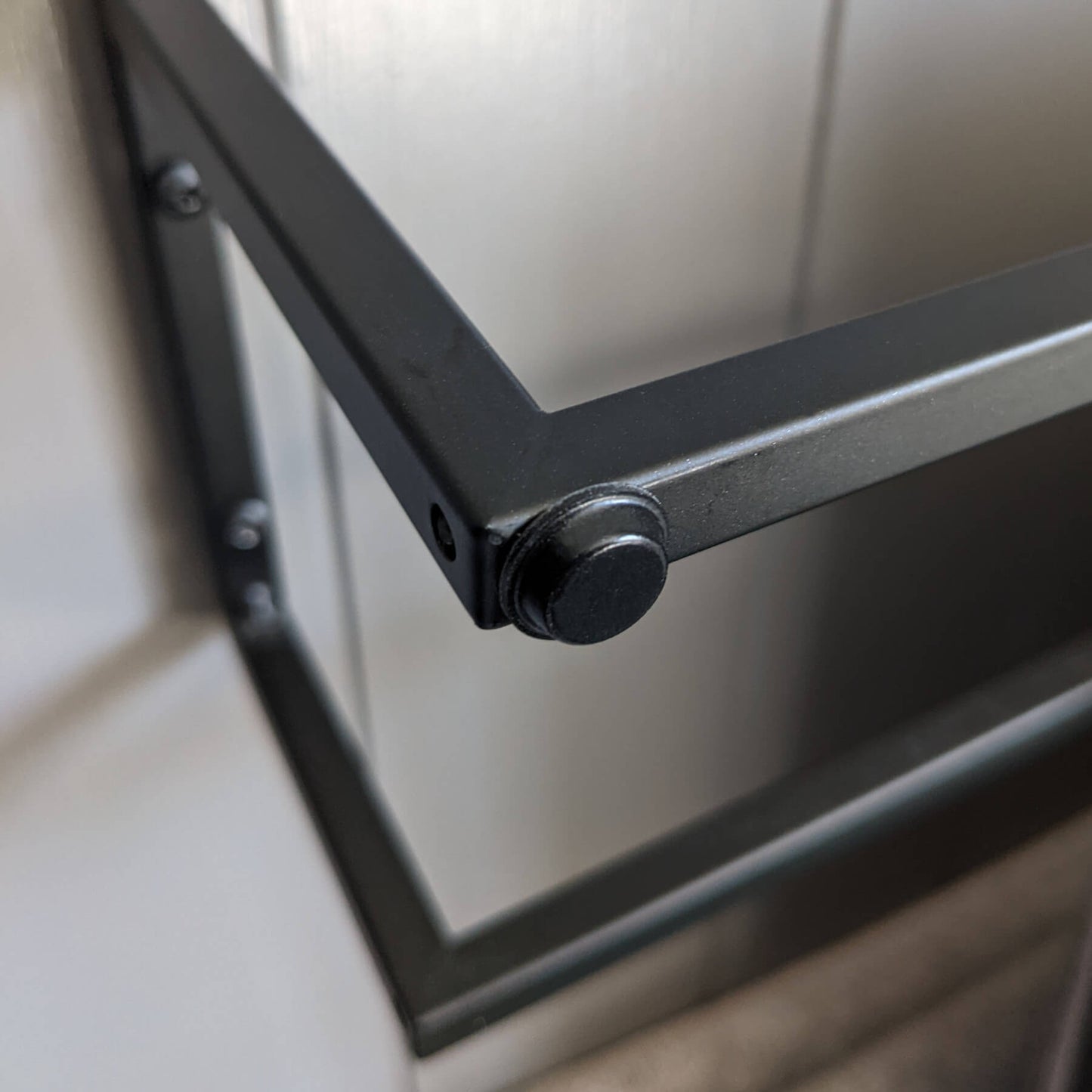 A black flat topped bumper pad used on the edge of towel rail to prevent damage to a door when it makes contact.
