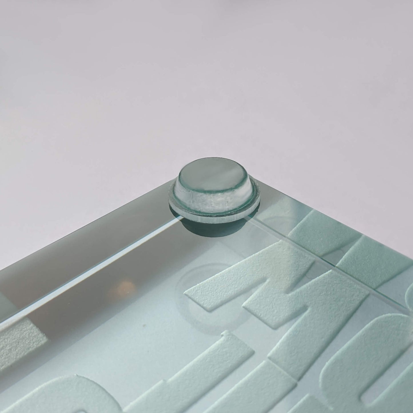 A close up of a single clear flat topped bumper being used on a glass paperweight.