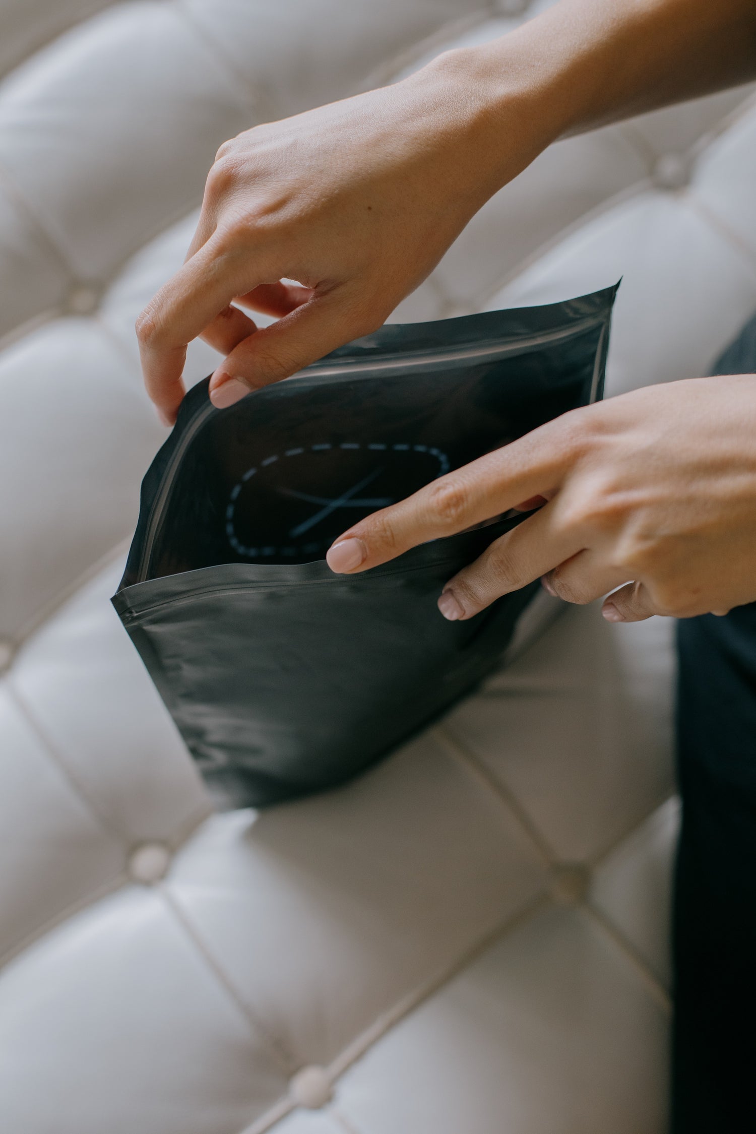 hands holding open a black postal envelope.