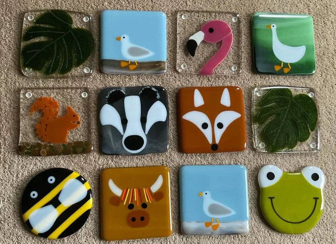 Twelve glass coasters featuring different designs.