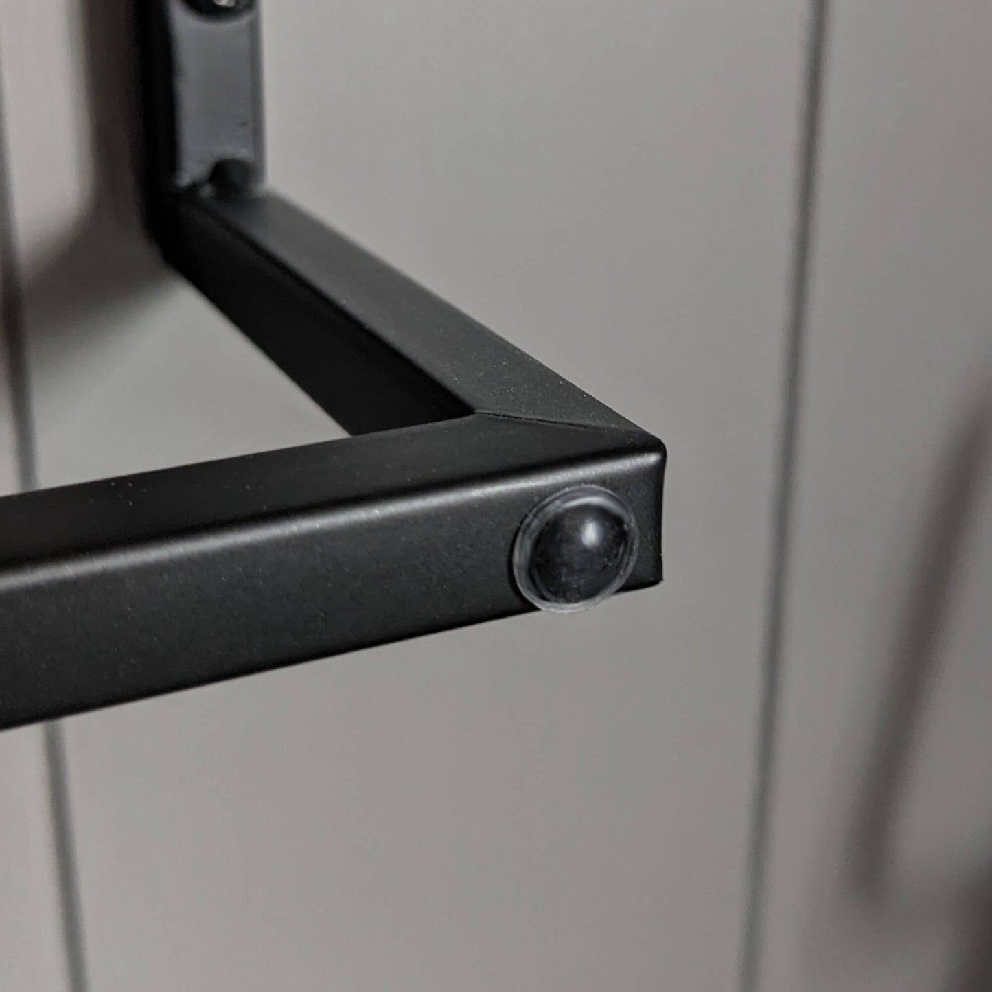 A clear domed bumper foot being used on the edge of a towel rail to stop a nearby door making contact with the towel rail.