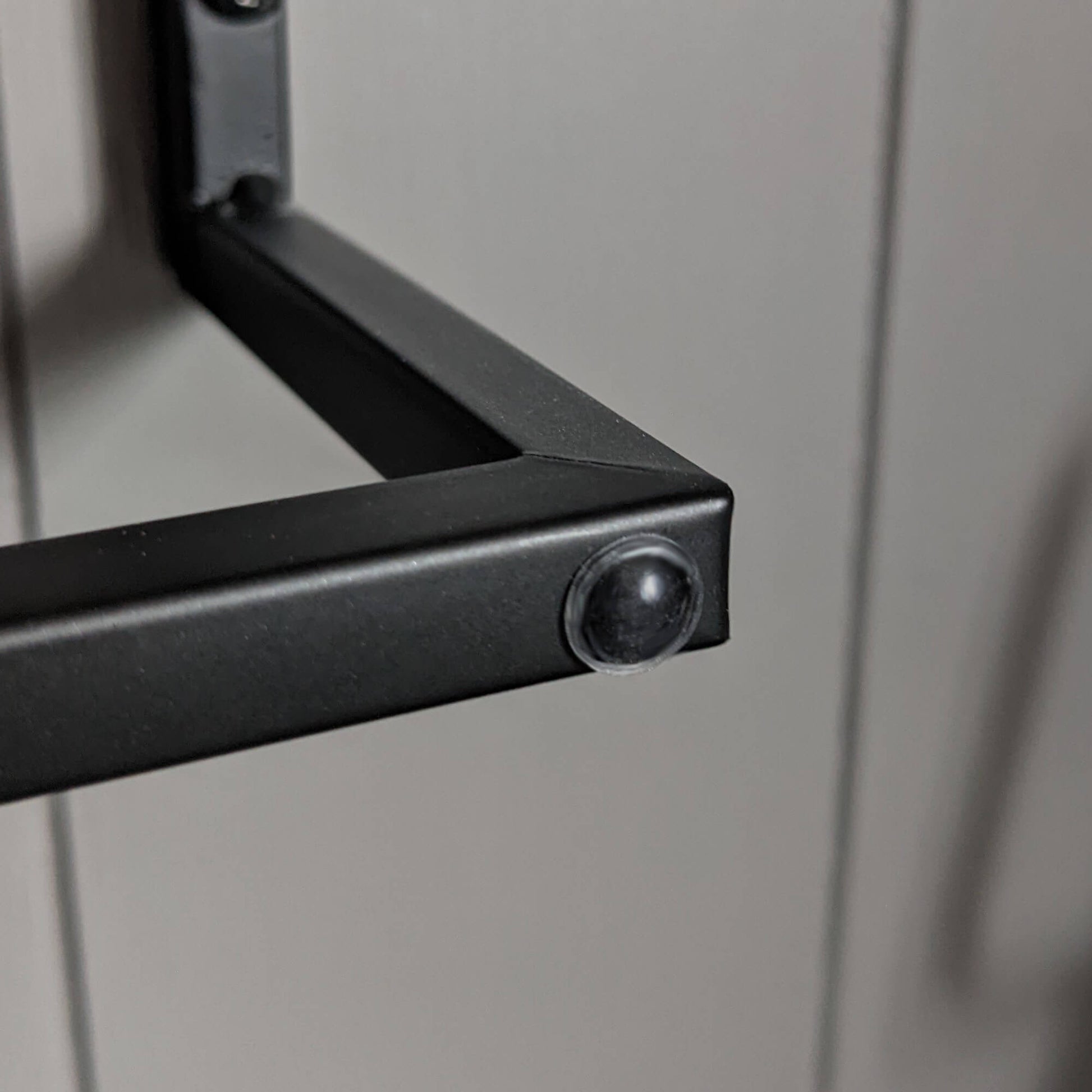 A clear domed bumper foot being used on the edge of a towel rail to stop a nearby door making contact with the towel rail.