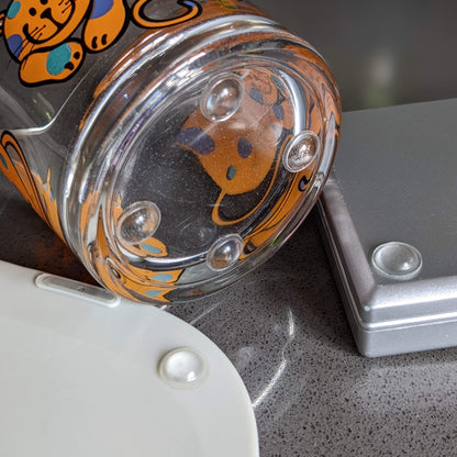 Clear domed bumper feet used on a glass jar base, a chopping board and a set of plastic electronic scales.