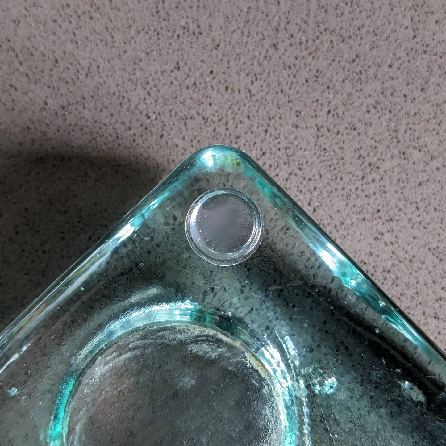 A single clear flat topped bumper stuck to the bottom corner of a tealight holder.