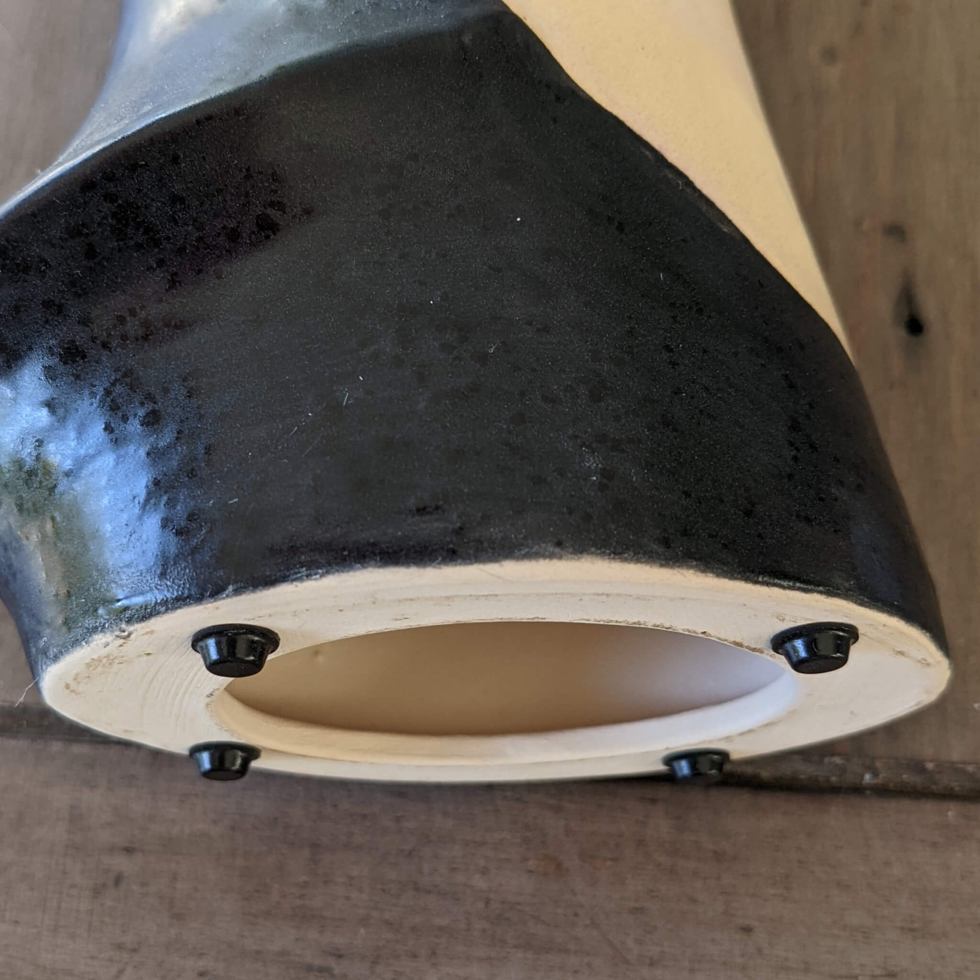 4 black mini flat topped bumper pads used n the base of a ceramic decorative item.