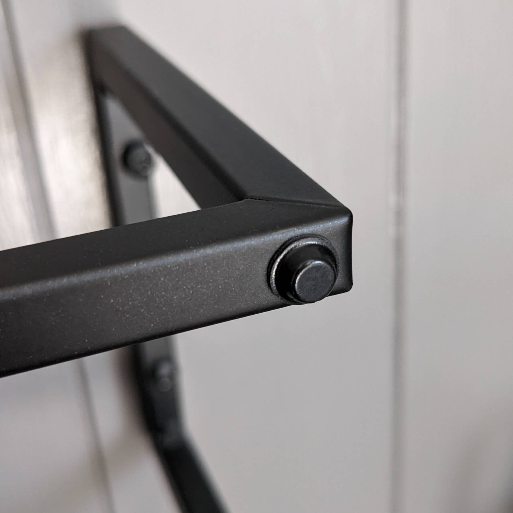 A mini black coloured flat topped bumper used on a towel rail to stop the rail from damaging a nearby door when opened.