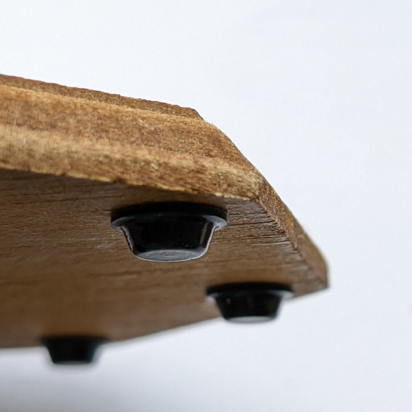 3 mini sized black bumper feet used on the base of a wooden coaster to prevent slipping and sliding.