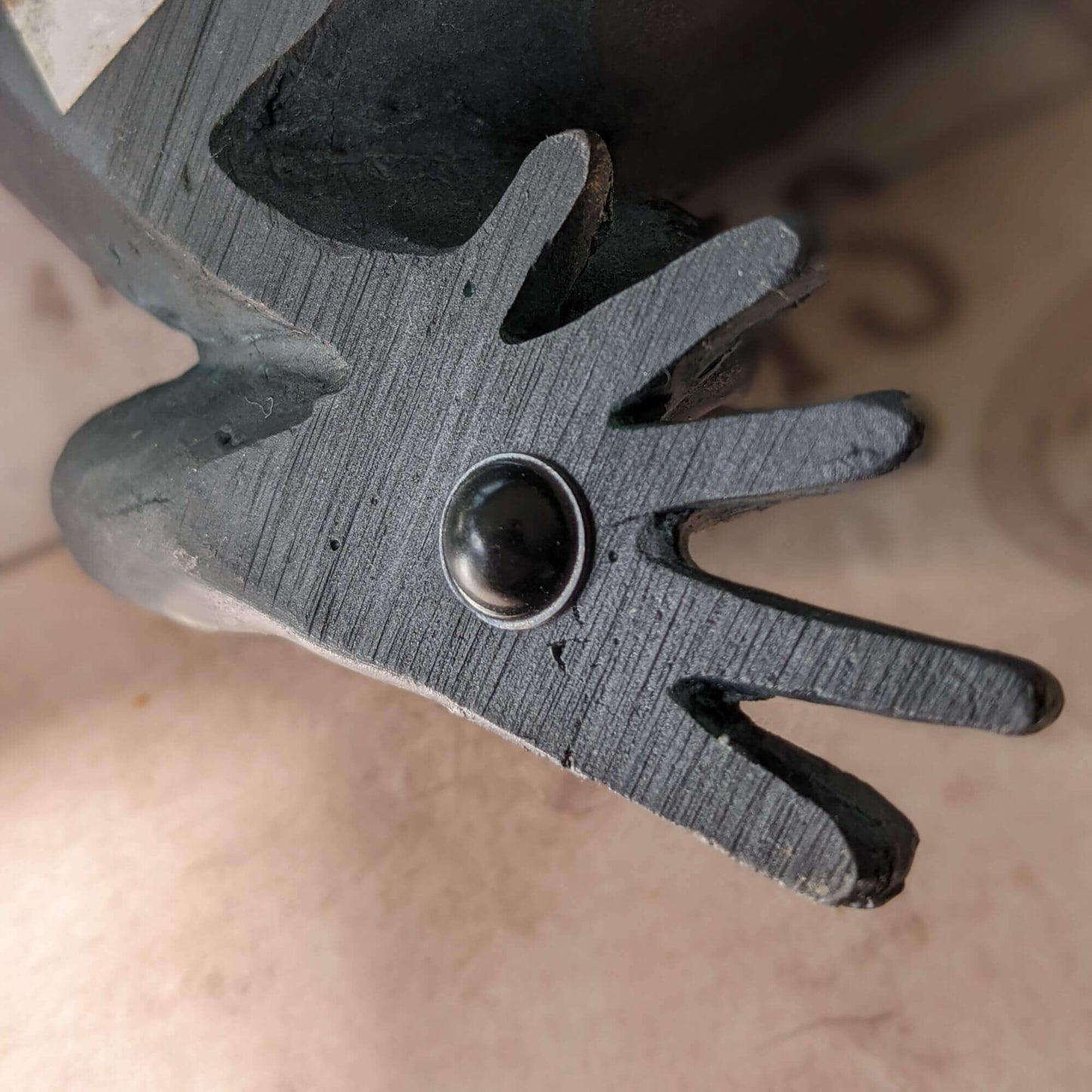 A single black bumper foot being used on the foot of a frog ornament.