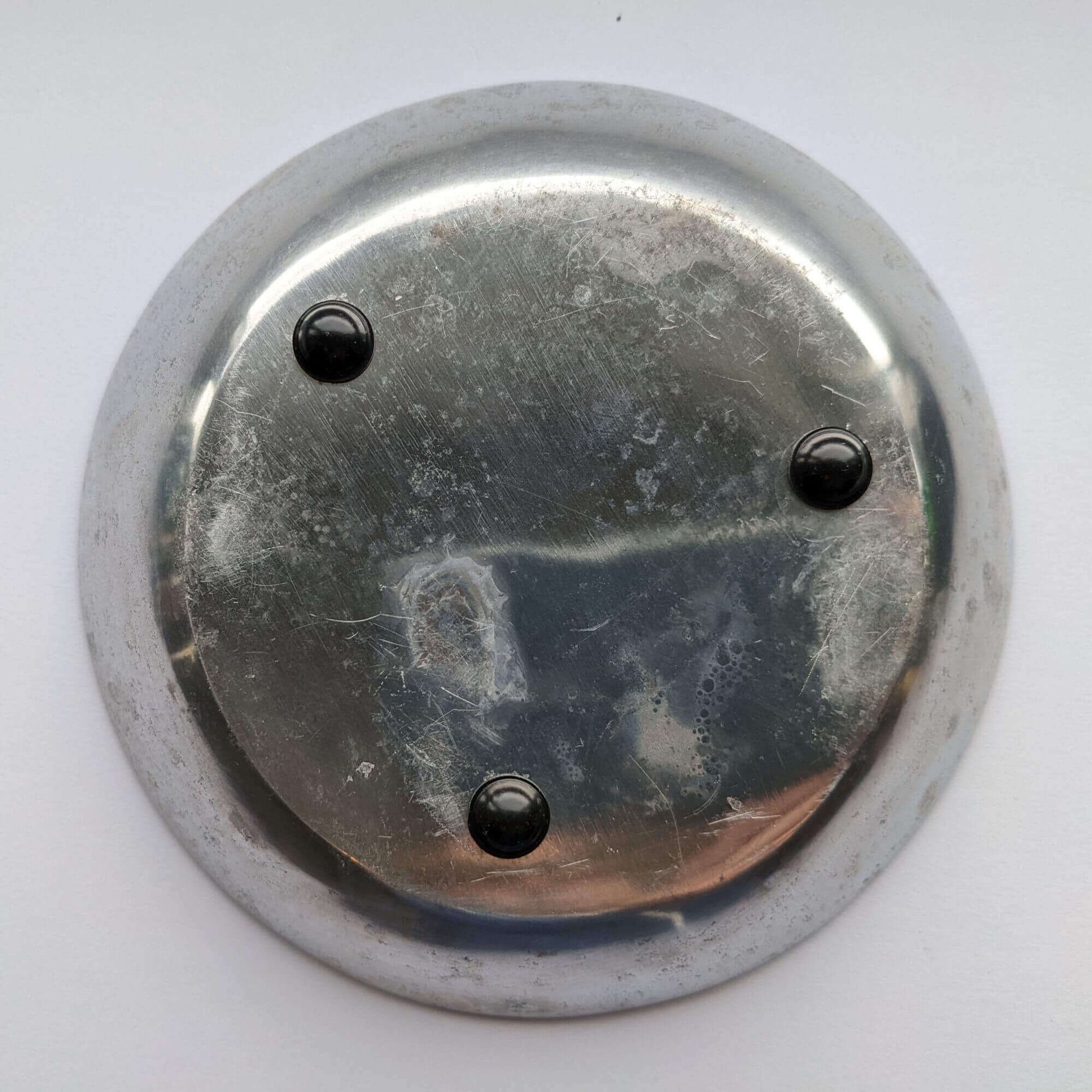 3 domed black bumper feet adhered to the base of a galvanized metal bowl.