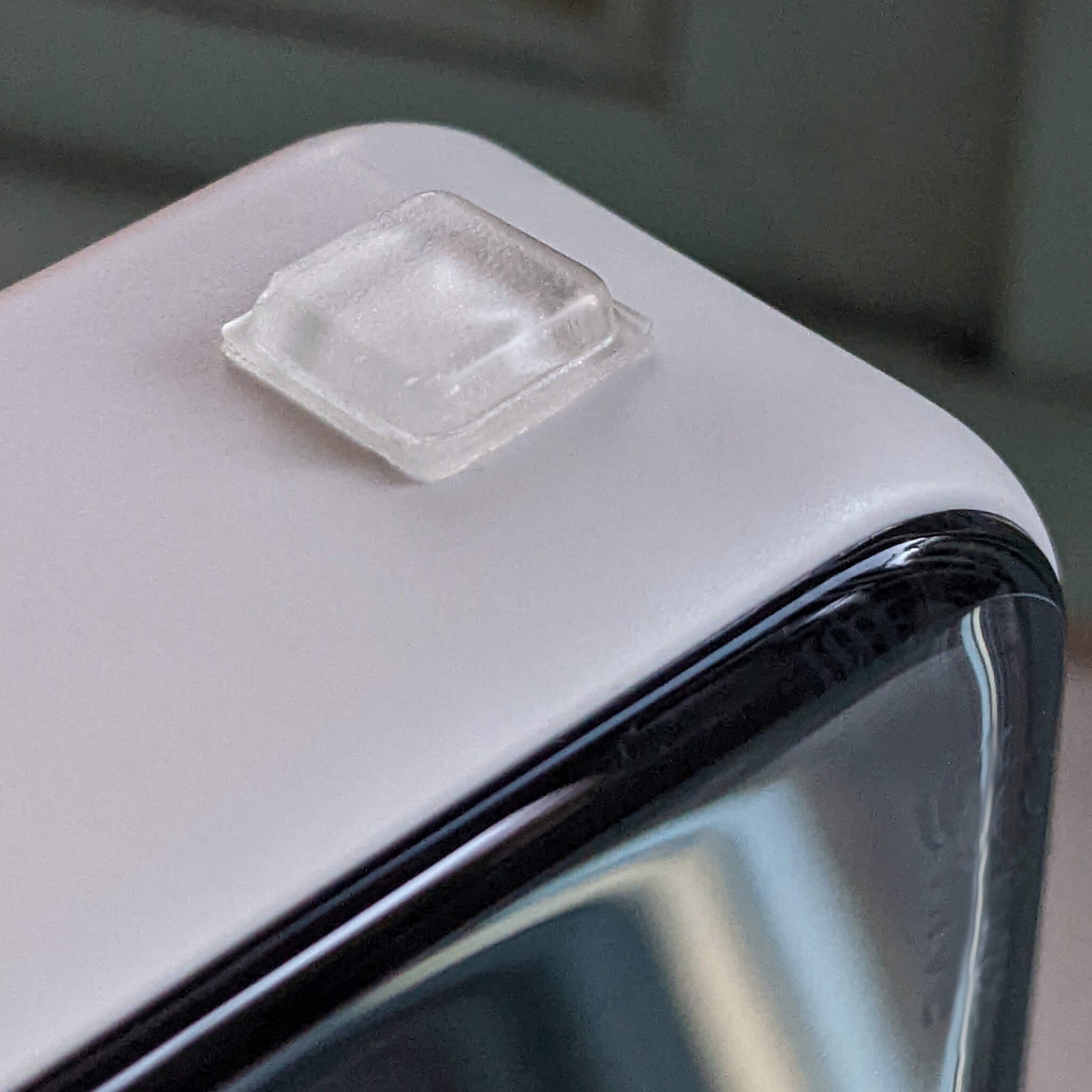 A single square bumper pad used on the bottom of an electronic unit to stop it moving.