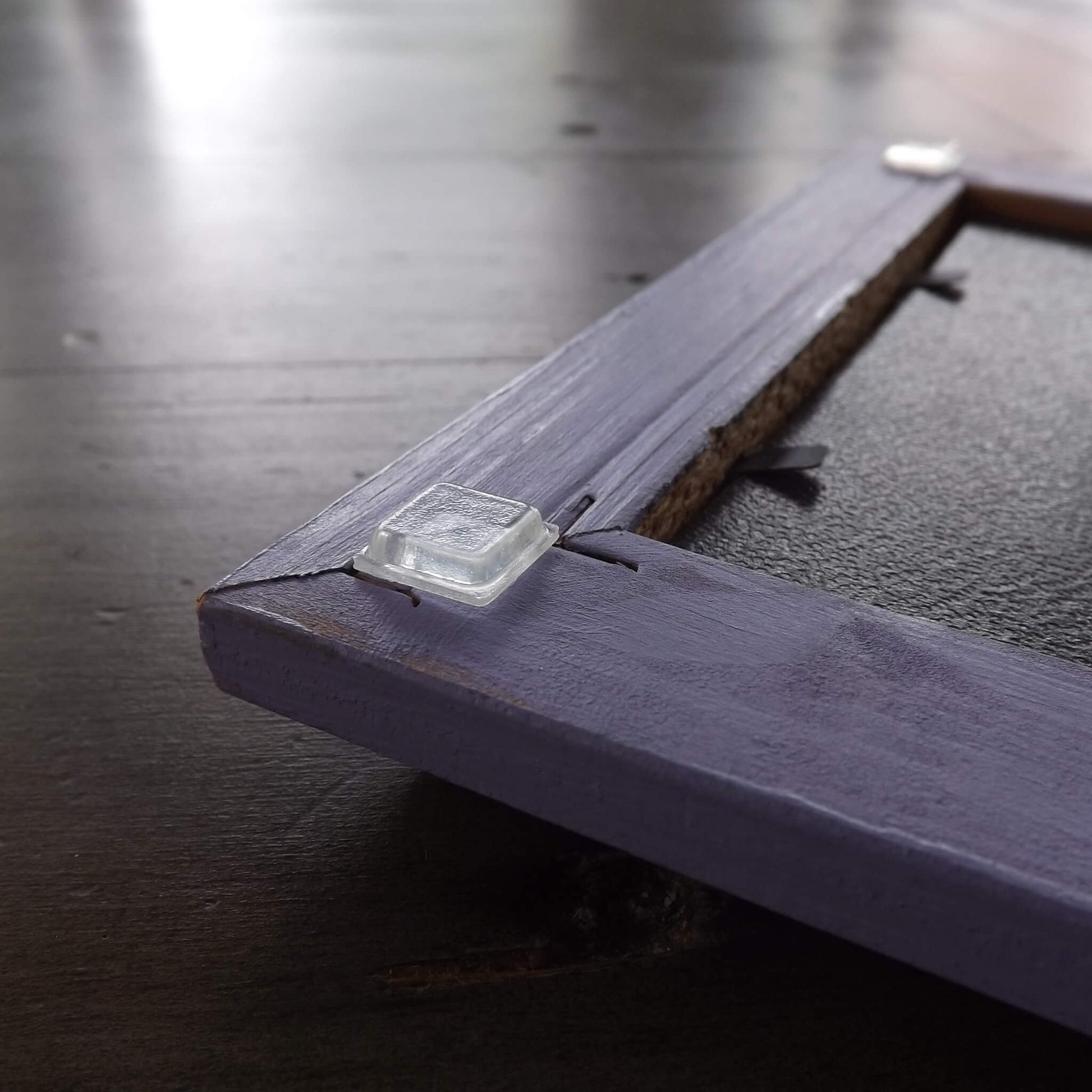 Square bumper feet being used on the corners of a picture frame to help stop marking of walls when hung.