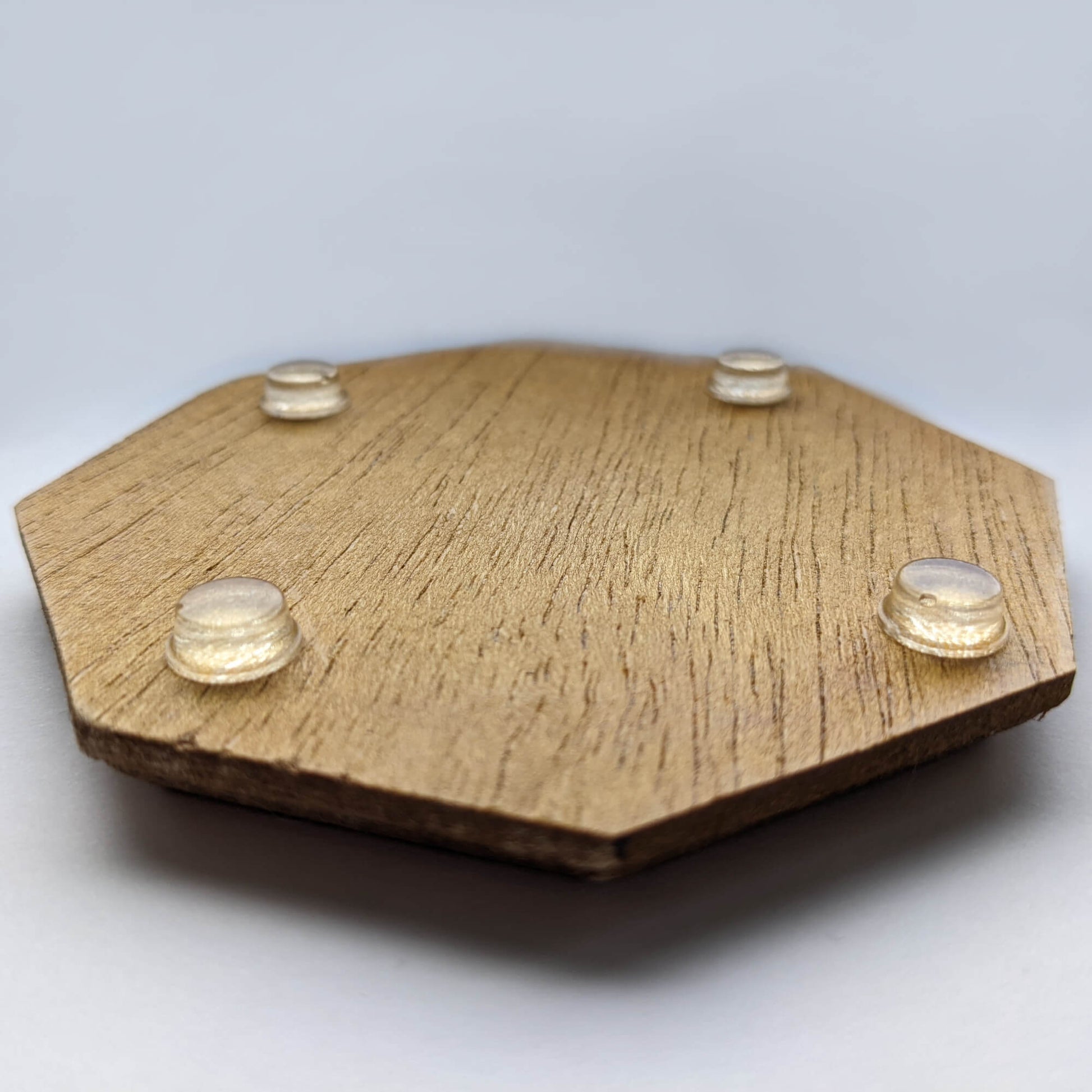4 clear flat bumper feet stuck to the base of a wooden coaster to prevent sliding.
