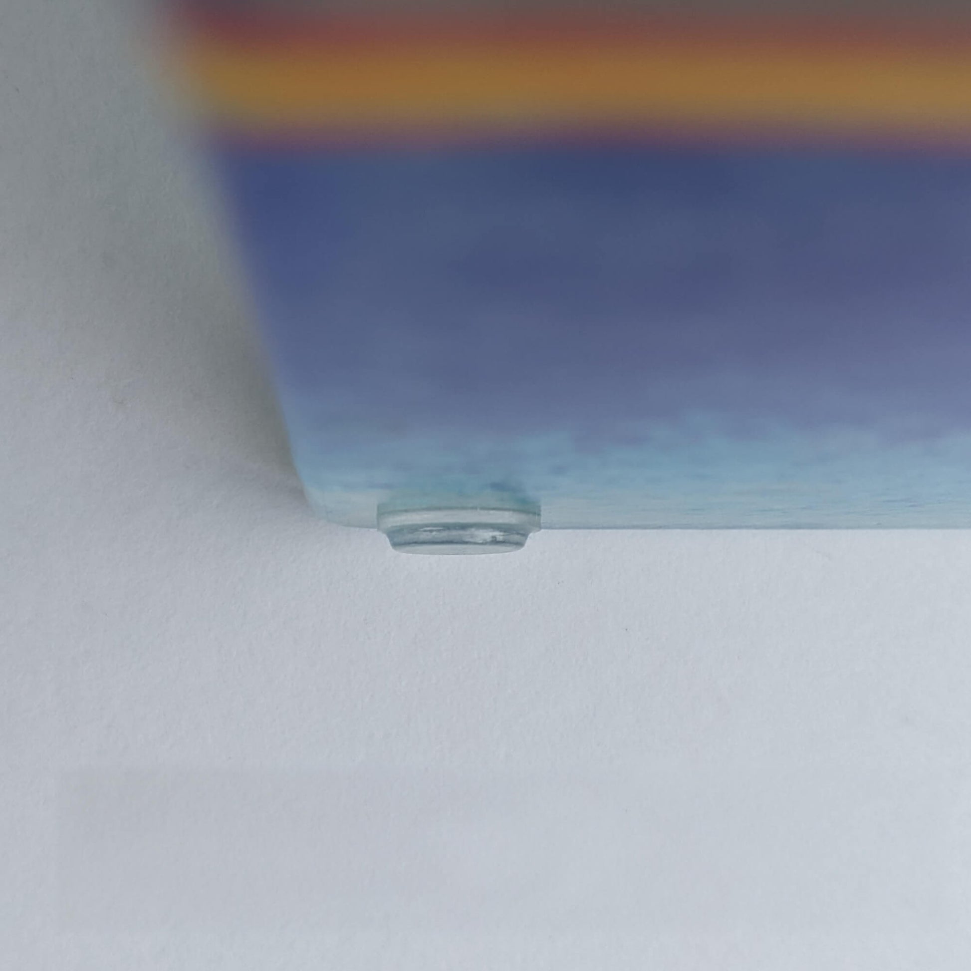 A clear flat bumper pad used on a glass coaster to help prevent movement.