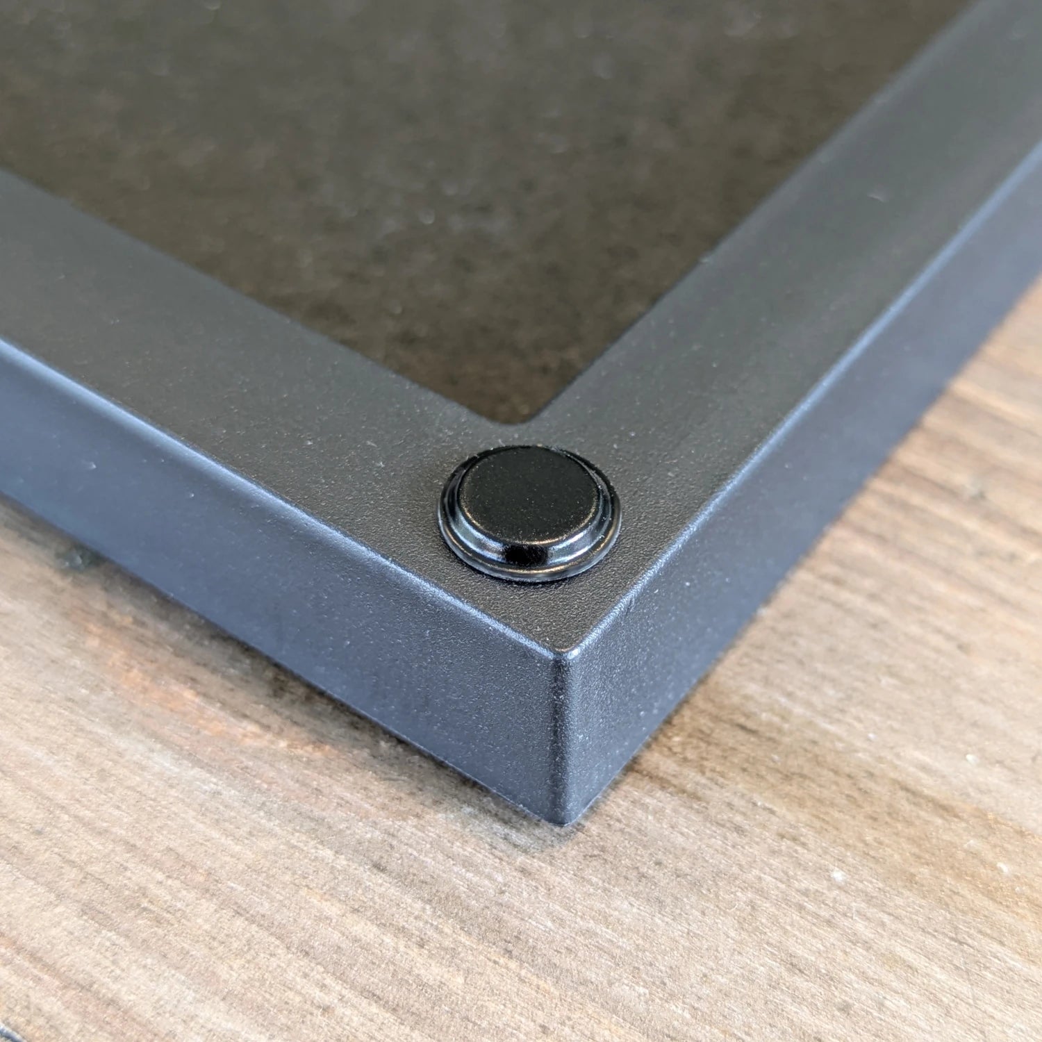 A black flat topped bumper pad used on the back of a picture frame to prevent wall marking.