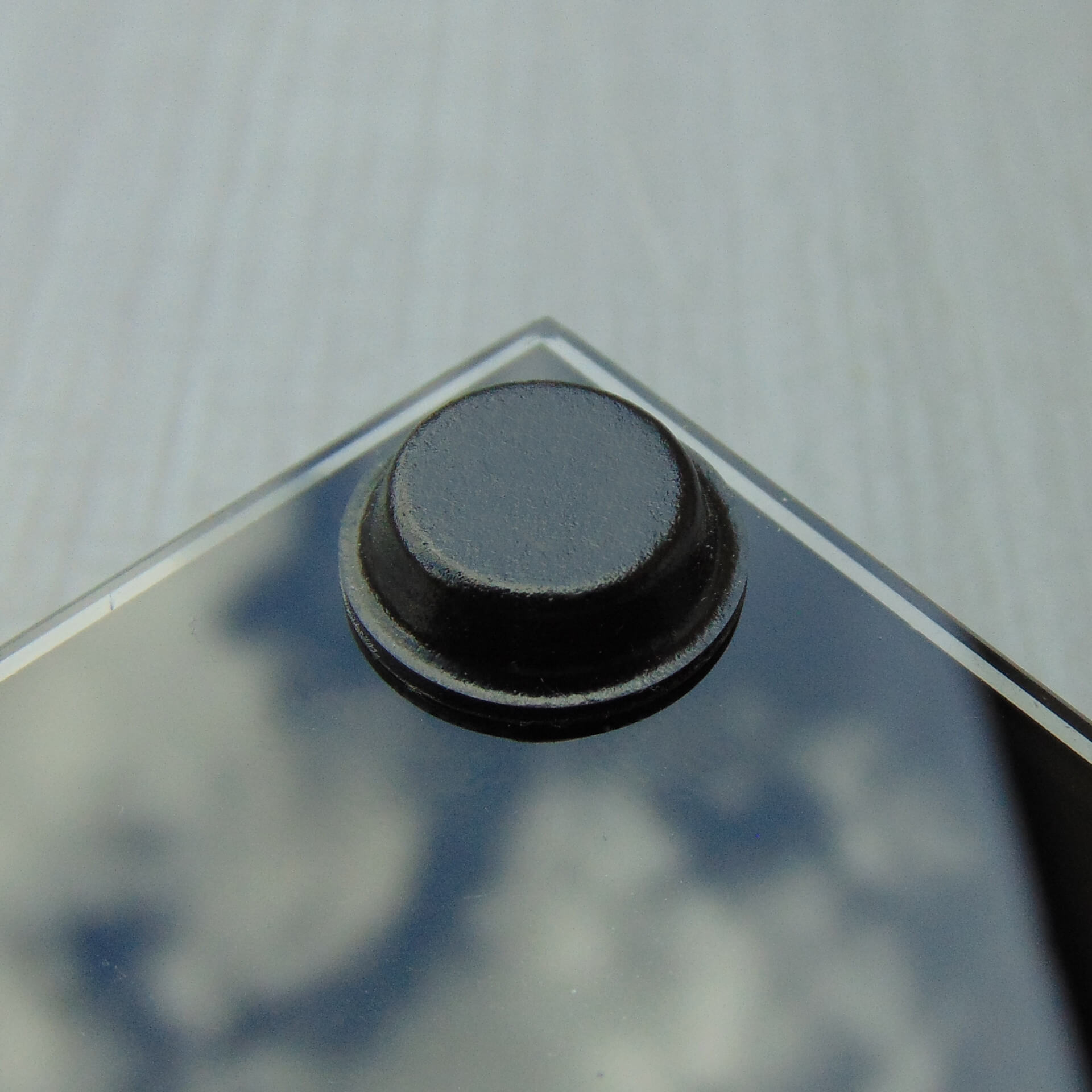 Black glass table-top with a black flat topped pad used to help prevent breakage of the glass.