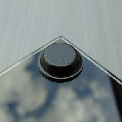 Black glass table-top with a black flat topped pad used to help prevent breakage of the glass.