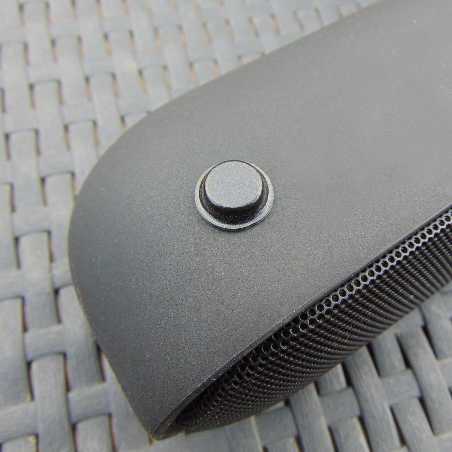 A black Bluetooth speaker with a black flat topped bumper pad being used to stop unwanted movement.