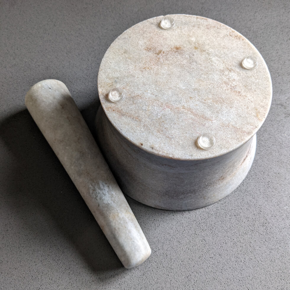An upside down pestle and mortar, with the mortar showing 4 clear bumper feet pads being used to prevent slippage.
