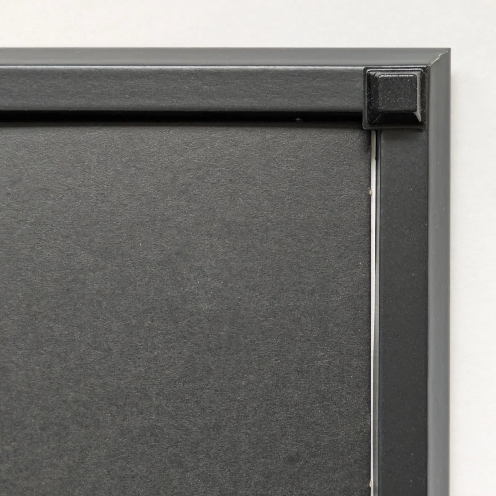 Close-up of a black square bumper used on the back corner of a black frame