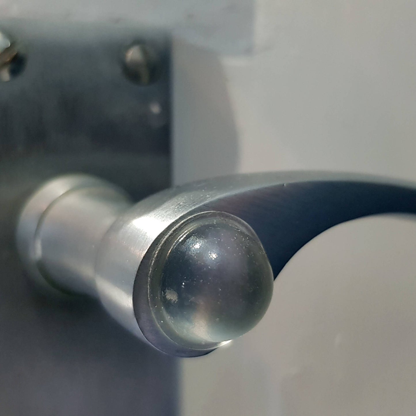 A domed bumper foot applied to a metal door handle, to stop the handle damaging a nearby wall when it makes contact.