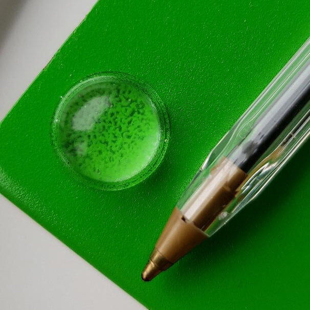A domed bumper applied to a decorative item placed next to a biro pen.