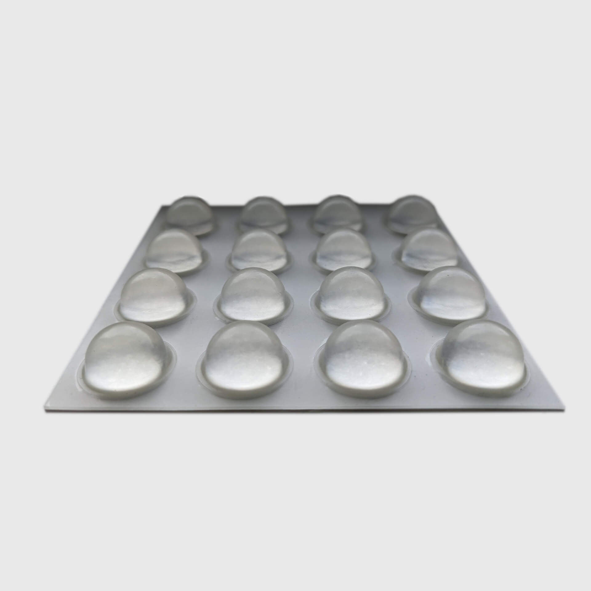 An adhesive backed sheet of 16 domed bumper feet.