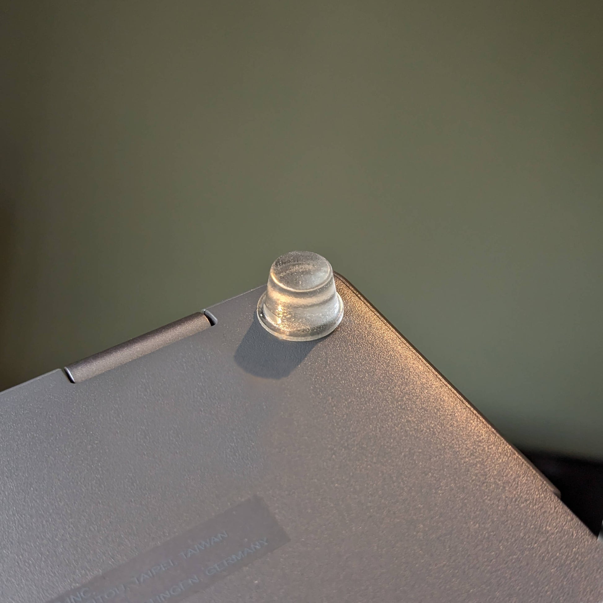 A tall clear bumper foot used on a laptop to aid airflow and stop unwanted movement.