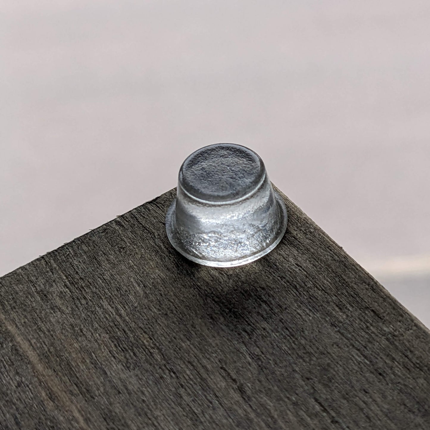 A clear tall bumper foot used on the corner of a wooden unit to give it stability.