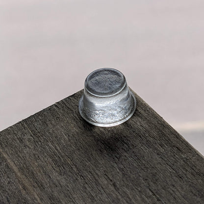 A clear tall bumper foot used on the corner of a wooden unit to give it stability.
