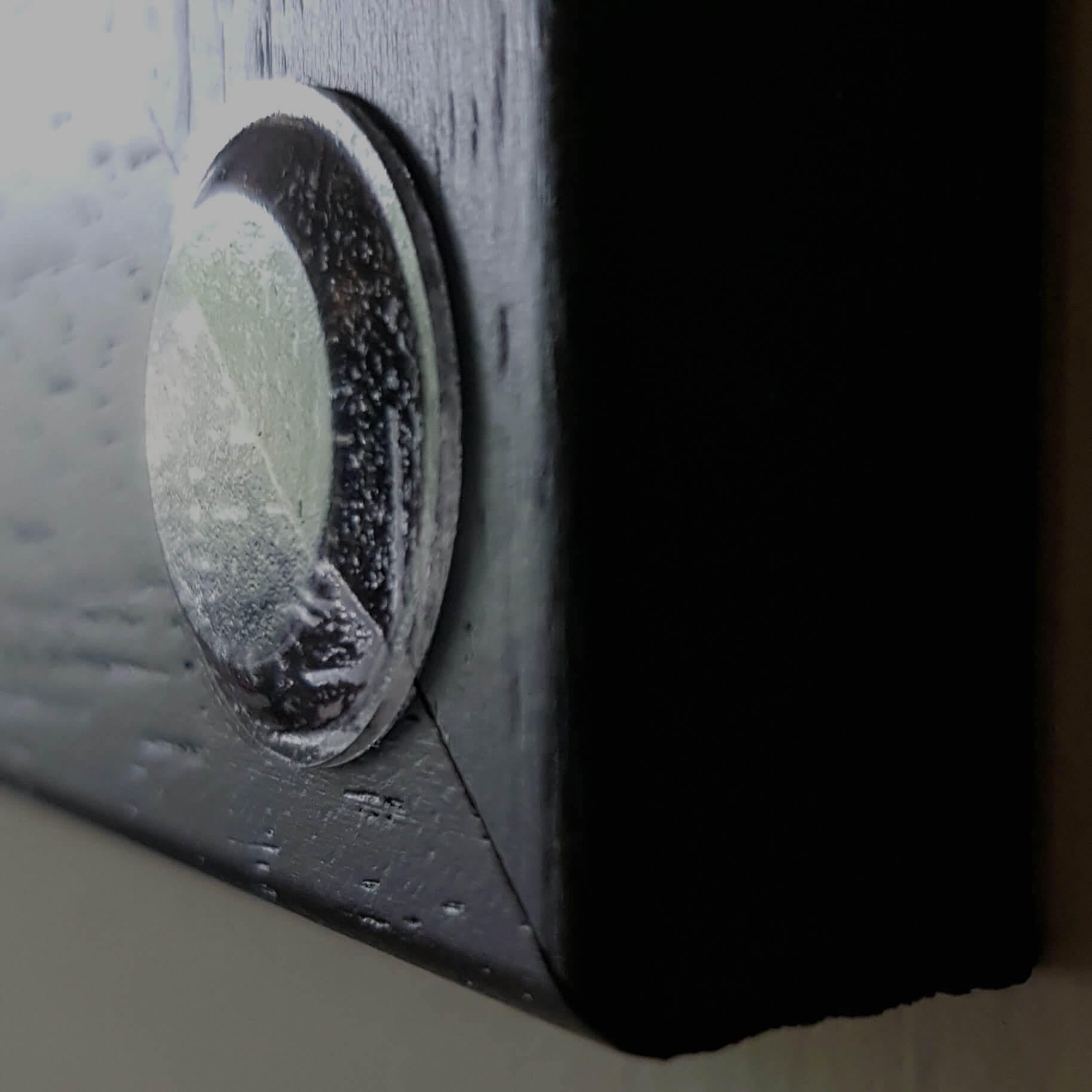 A low profile coasted used on a black painted wooden frame edge.