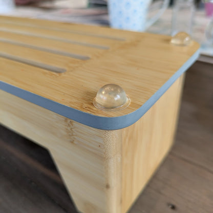 Clear domed bumper feet used on the base of a wooden chopping board rack.